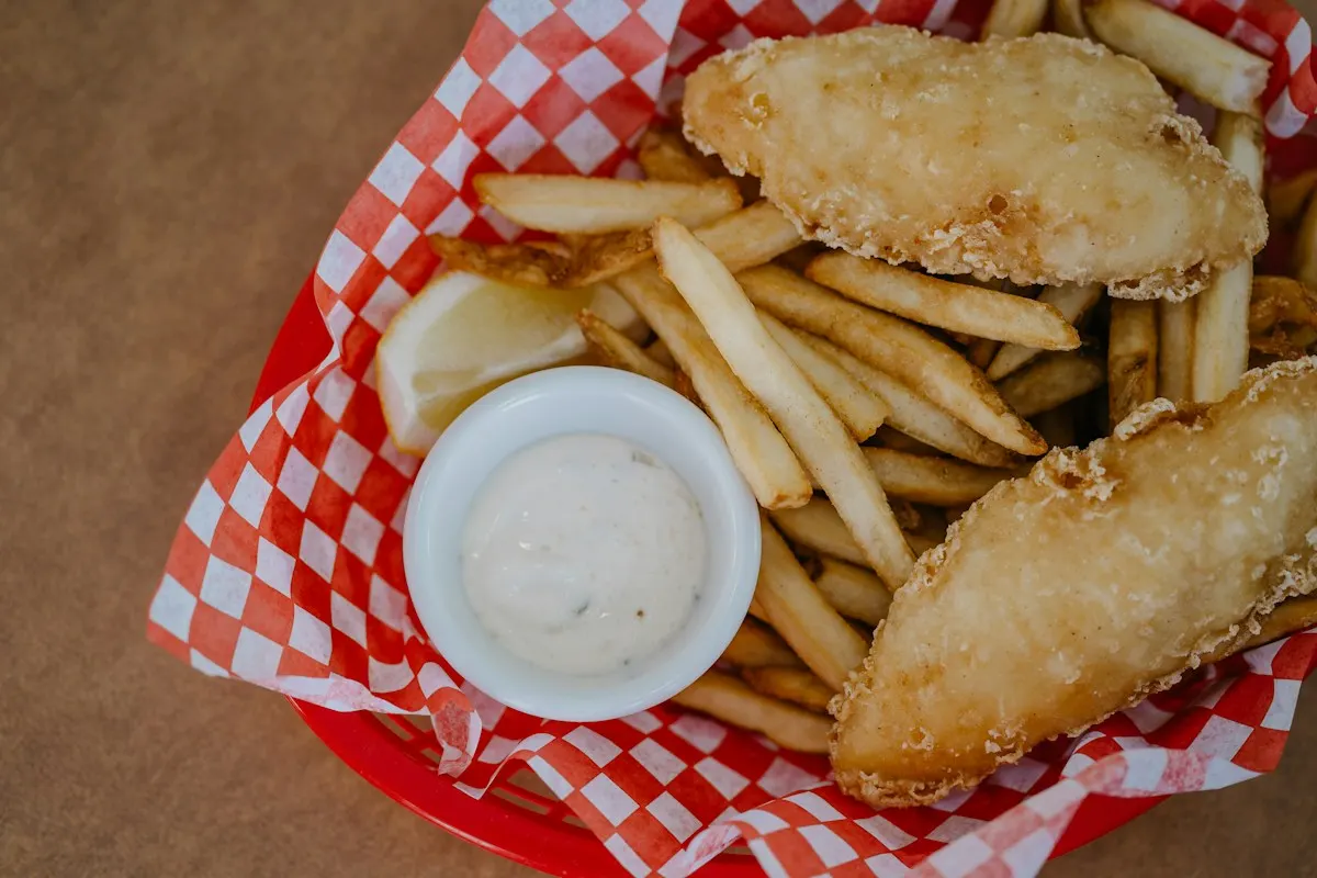 Battered fish and chips in a basket lined with red and white paper